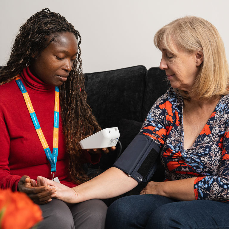 Carer assisting client with blood pressure monitoring