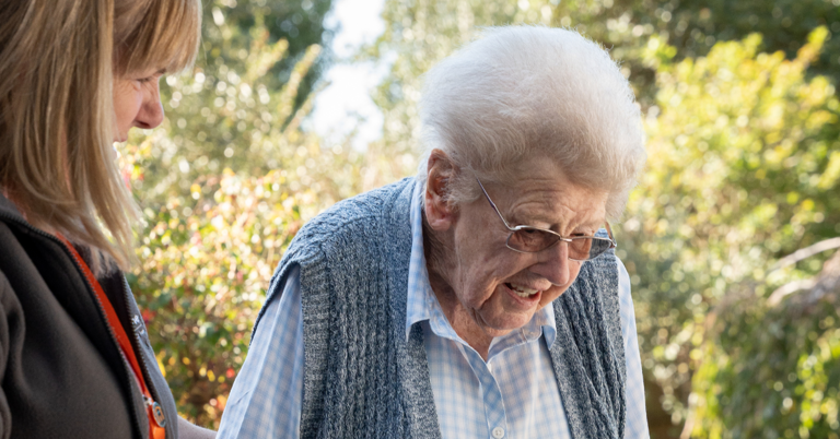 Client being supported by her carer outside, enjoying a safe and happy moment together.