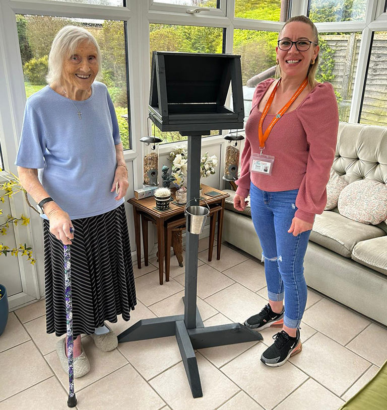 Client and Carer pose with bird house in conservatory