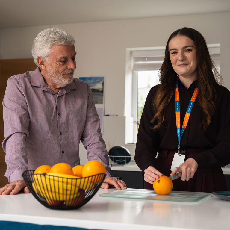 A carer cutting an orange for a client