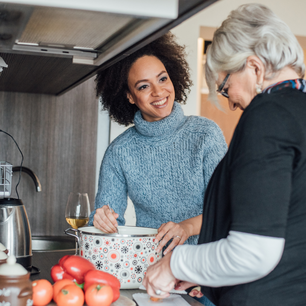 Older mother and daughter laughing together in the kitchen at home