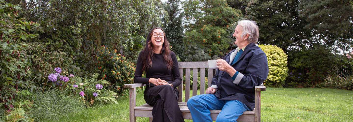 homecare client and caregiver laughing on bench