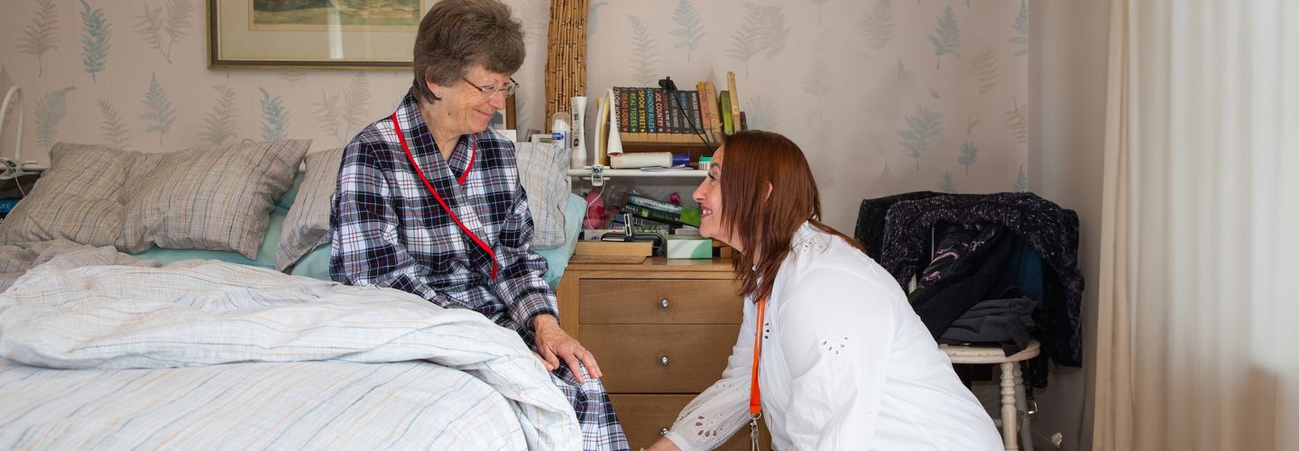 Image of a carer helping an elderly patient put on her shoes