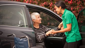 Carer assisting a client out of the car