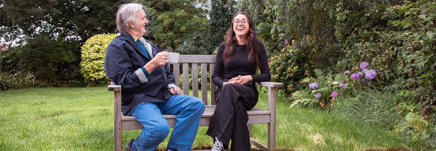 CareGiver and Parkinson's Client laughing on bench