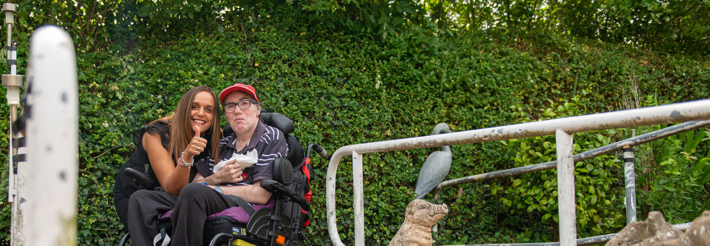 Client in wheelchare and CareGiver with her thumb up