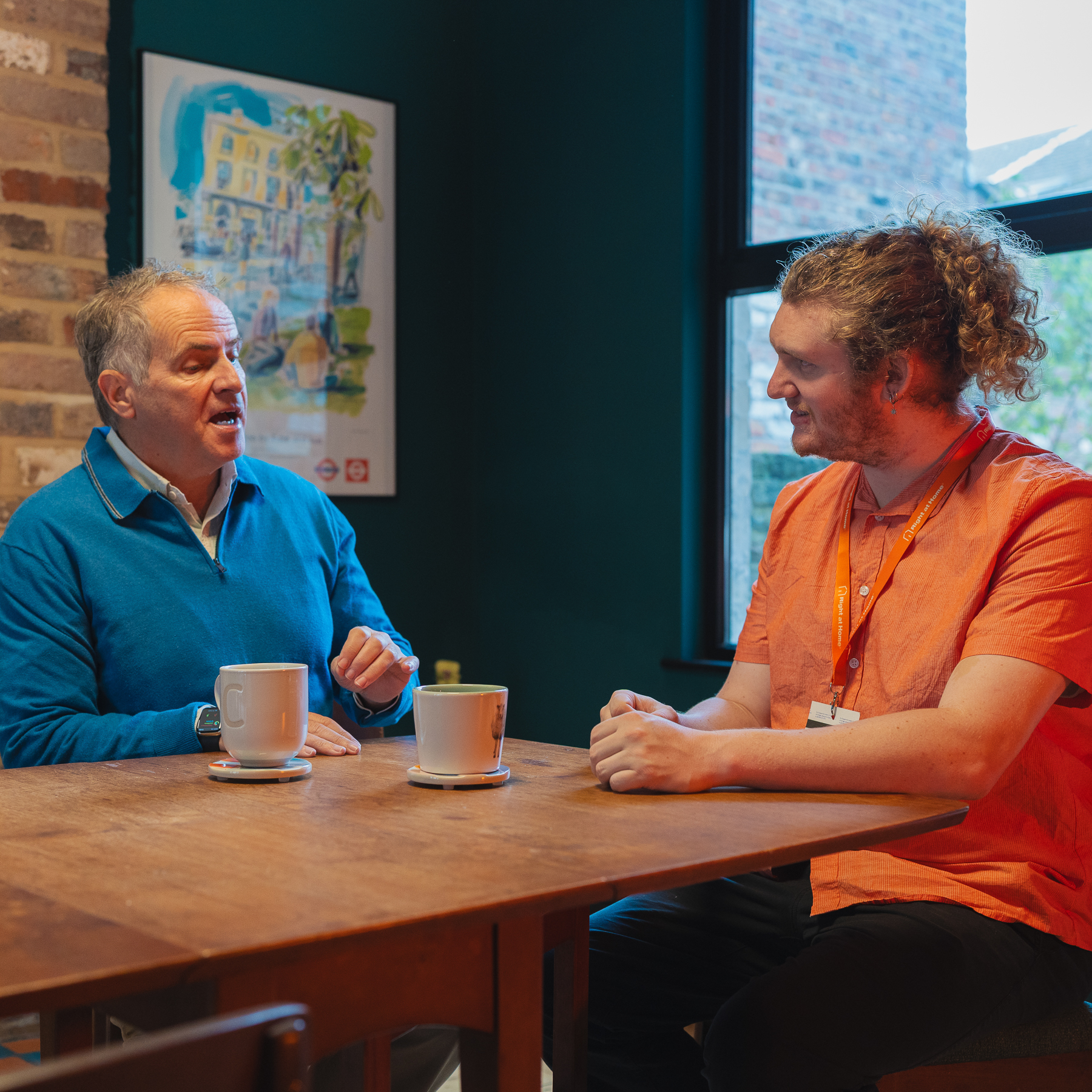Client and carer sharing a calm conversation at home during a care visit.