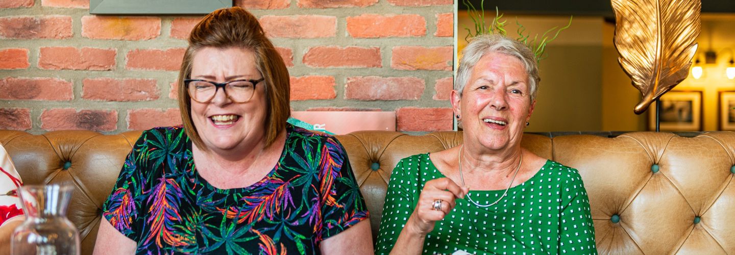 Client and CareGiver laughing on a sofa