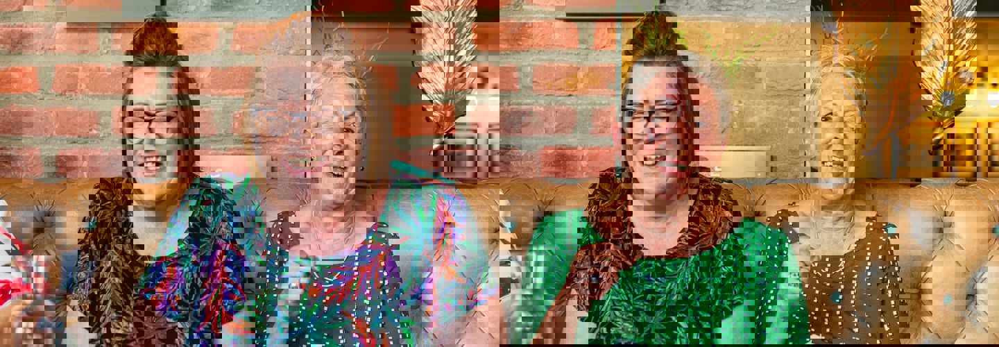 Client and CareGiver laughing on a sofa