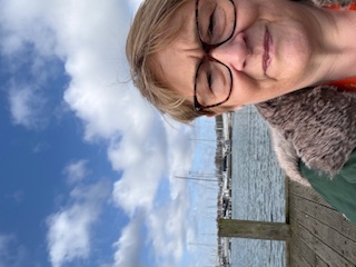 Paula, Community Engagement & Partnership Lead at Right at Home Solent, standing by the sea in Warsash during a community visit