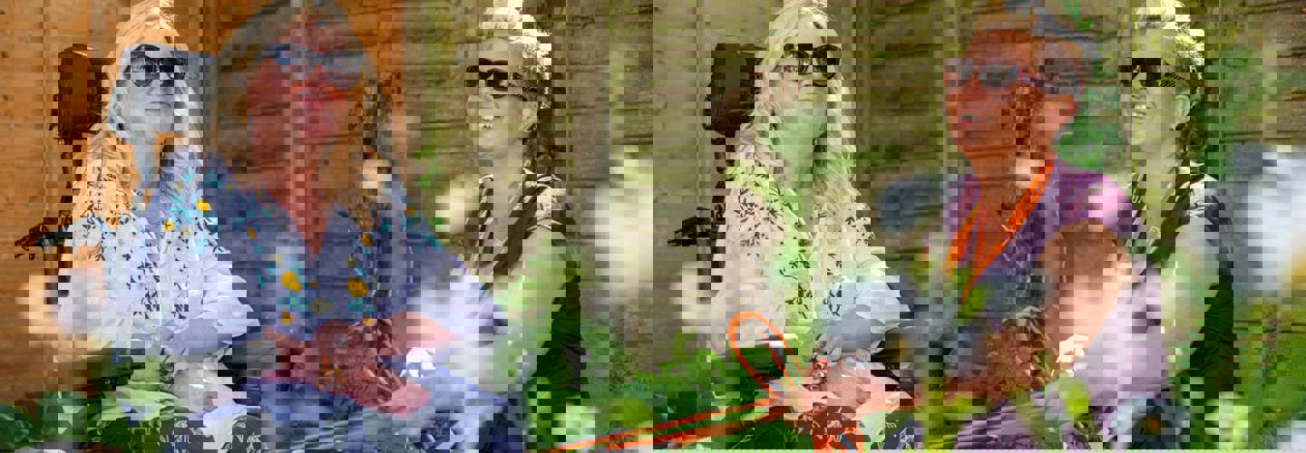 Two women sitting in a garden wearing sun glasses