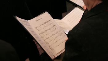 Person holding sheet music and singing