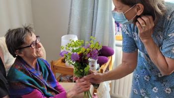 Woman gifting someone colourful flowers.