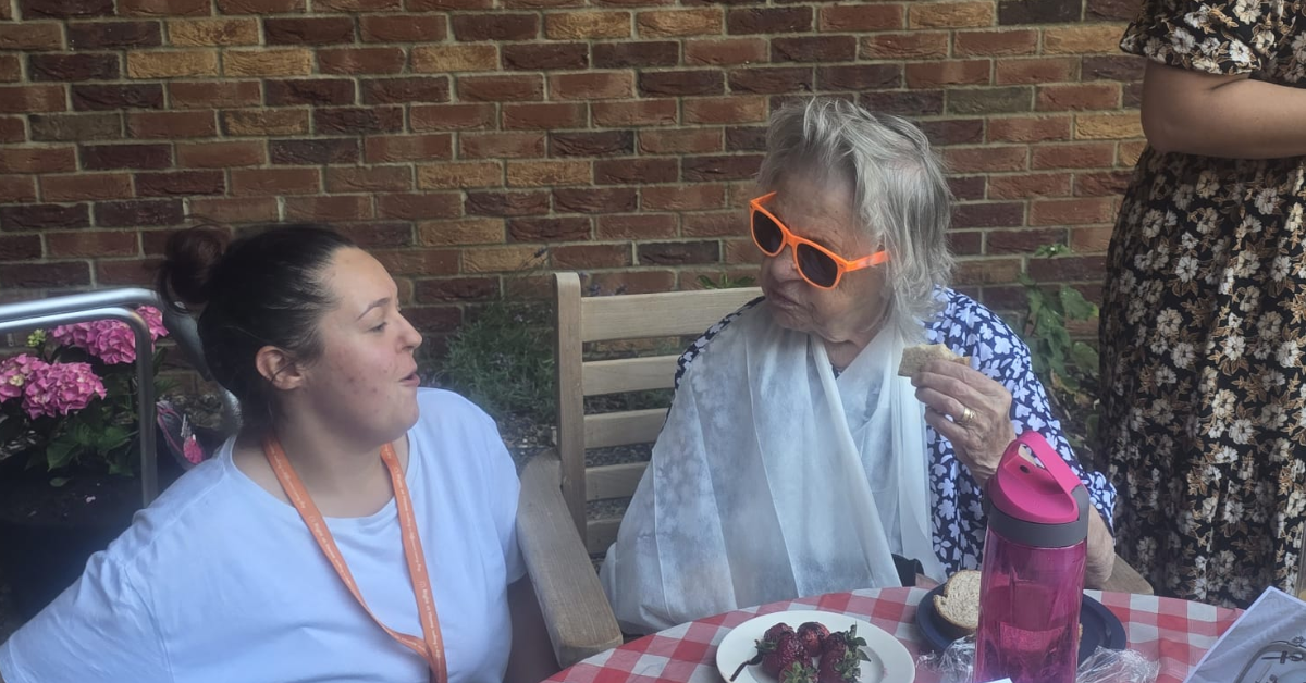 Care Assistant chatting with a client while they enjoy refreshments at the Big Green Picnic.
