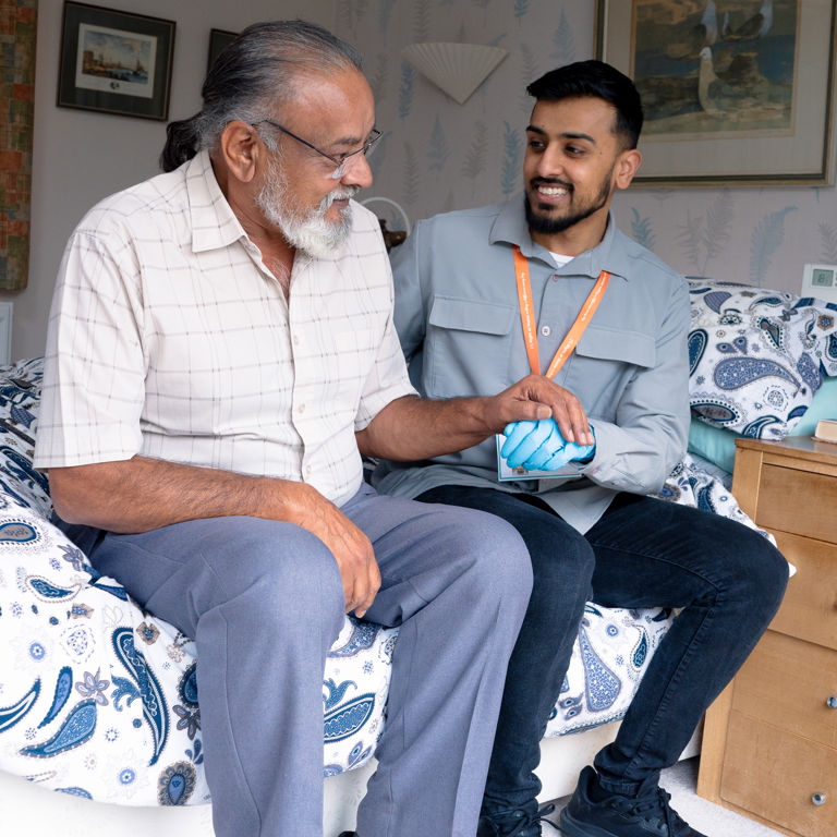 Carer supporting client sitting on bed