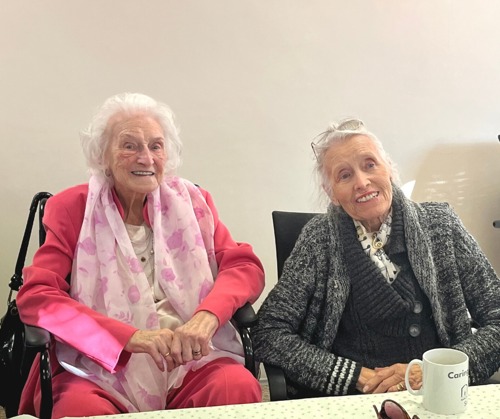 Two elderly ladies smile looking at the camera