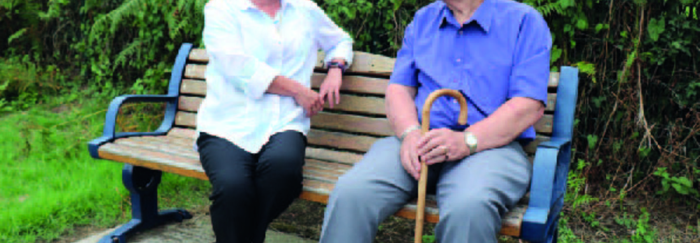 two people sitting and talking on a bench