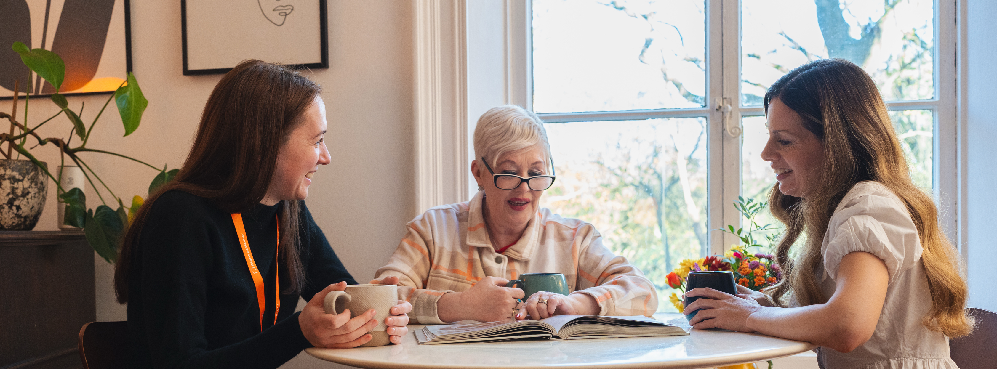 Adult daughter visiting elderly mother at home sharing tea and conversation
