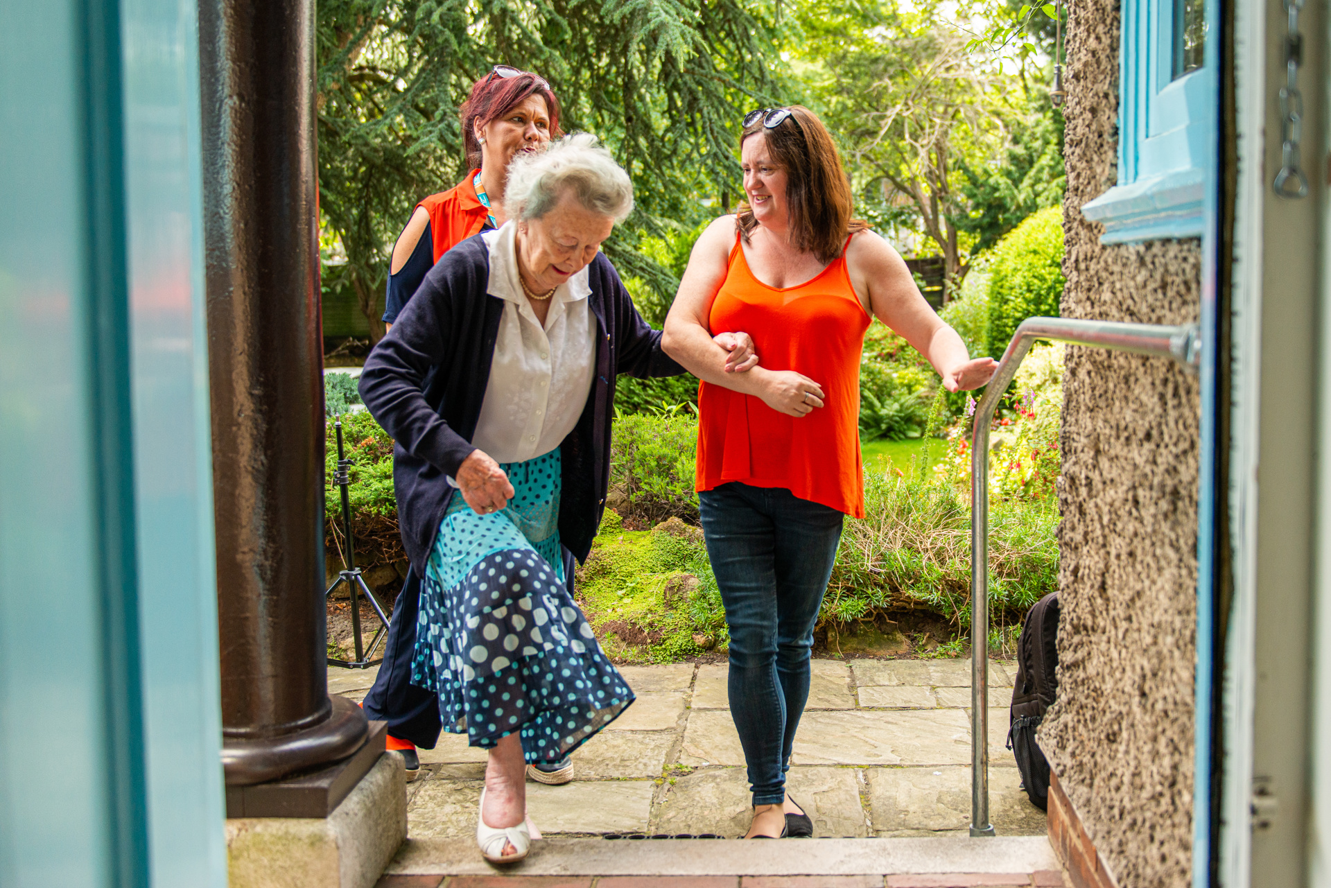 Caregivers supporting client steps into door