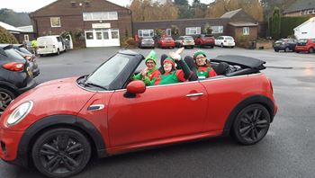 Three elves in a red convertible.