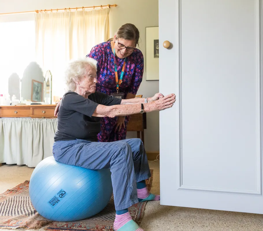 Reablement Client using exercise ball with assistance from Carer