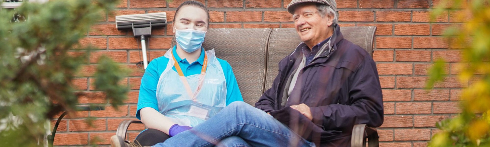 Caregiver and elderly gentleman sitting on bench