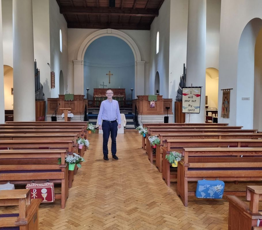 man standing between pews in church in knebworth