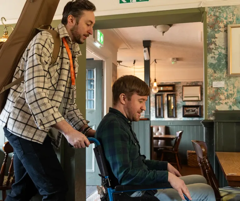 Wheelchair user and carer entering local public house