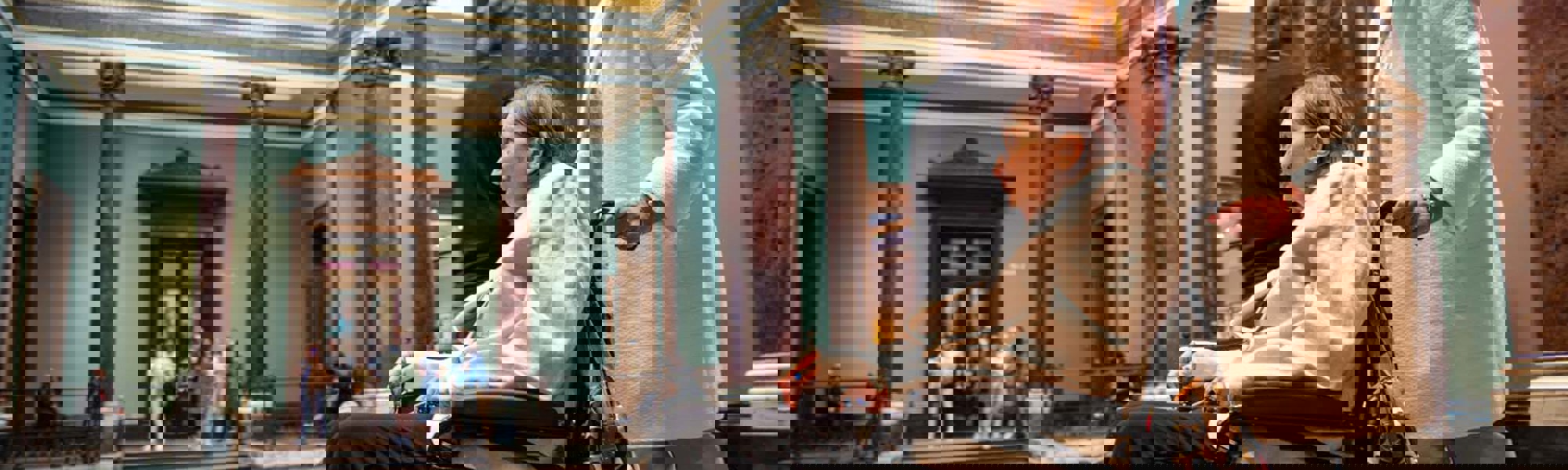 Client in wheelchair being pushed by CareGiver through a museum