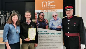 Smiling man and woman with a certificate. Man in military uniform on right of image.