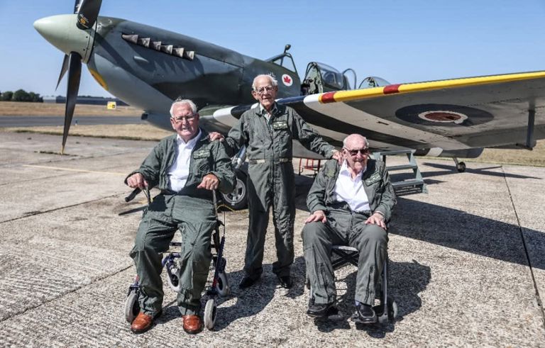 right at home client and others pose next to spitfire plane