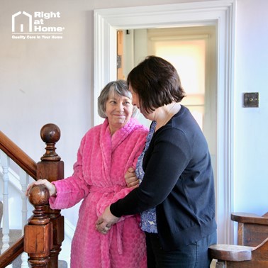 Female carer helping female client down stairs