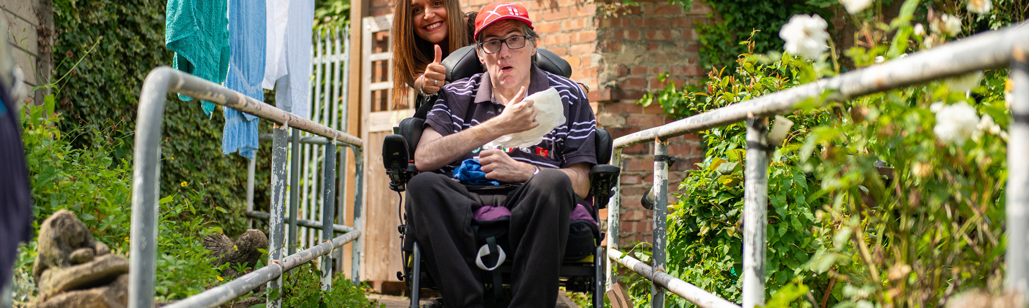 Client in wheelchair with CareGiver giving a thumbs up