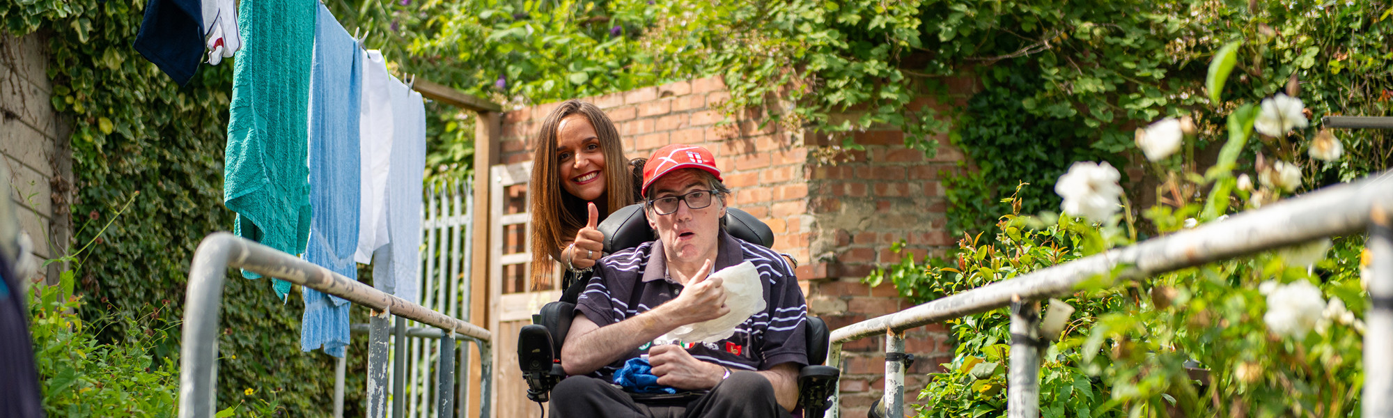 Client in wheelchair with CareGiver giving a thumbs up