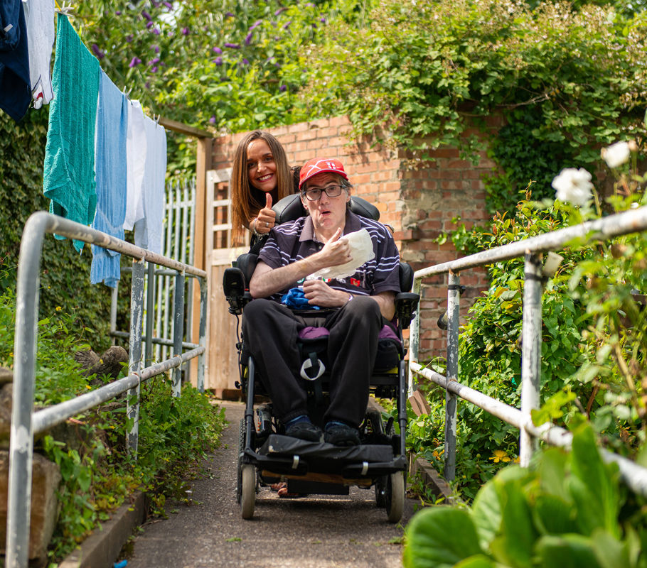 Client in wheelchair with CareGiver giving a thumbs up