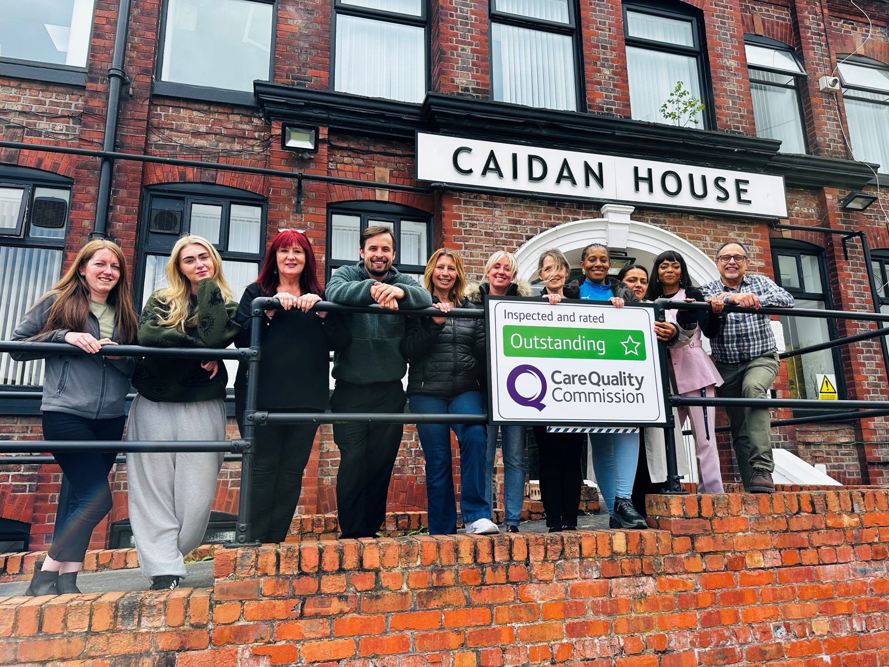Care professionals pose with Outstanding rating banner
