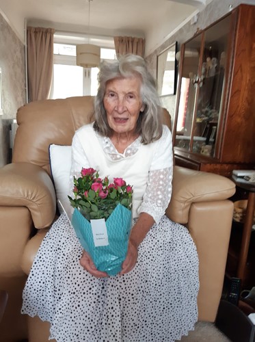 One of Right at Home Portsmouth's female clients holding a pot of flowers gifted to her by a Carer