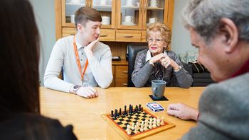 Homecare worker playing chess in the community with client