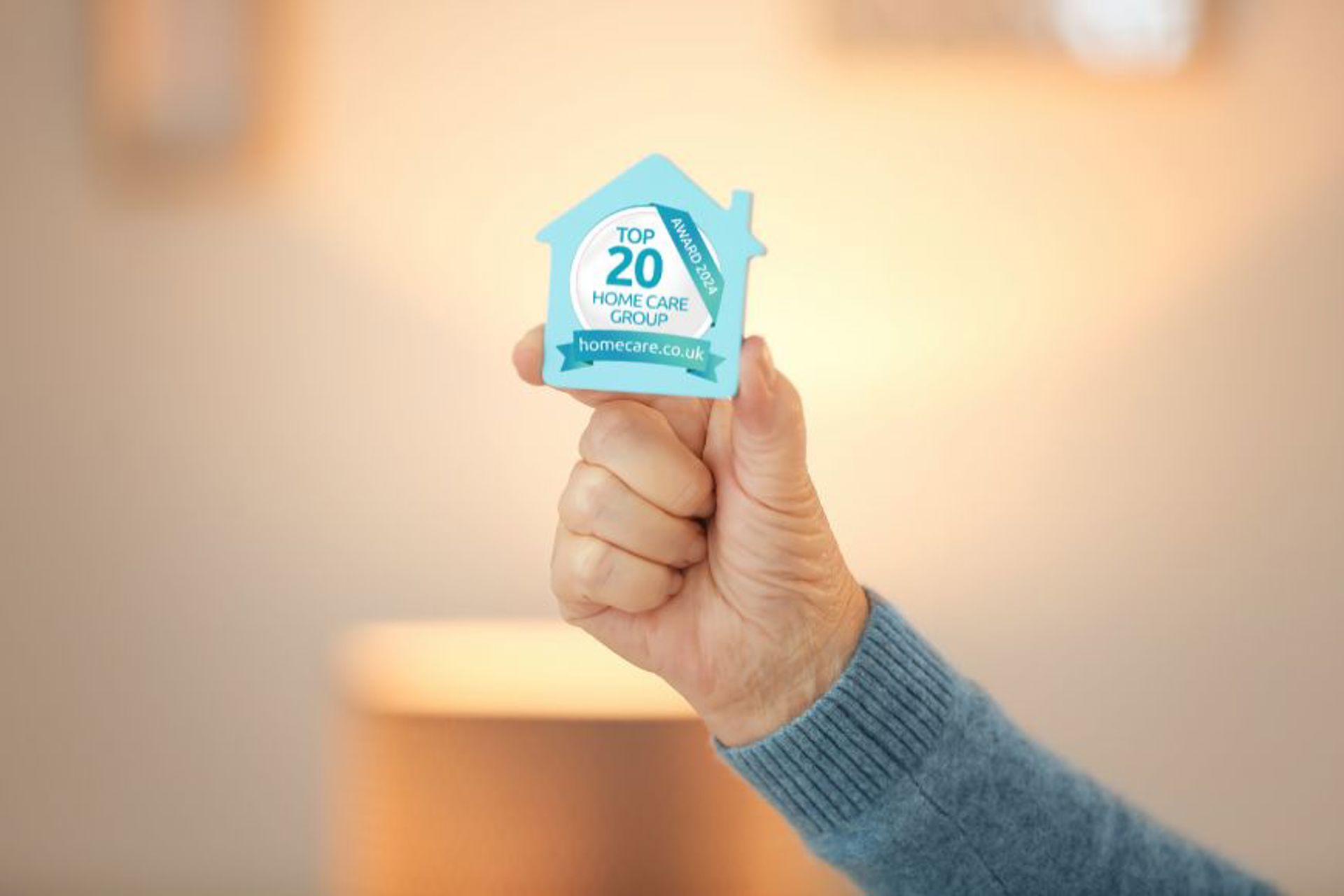 an-elderly-lady-holding-a-small-home-badge-with-the-top-20-home-care-group-award-logo-on-it