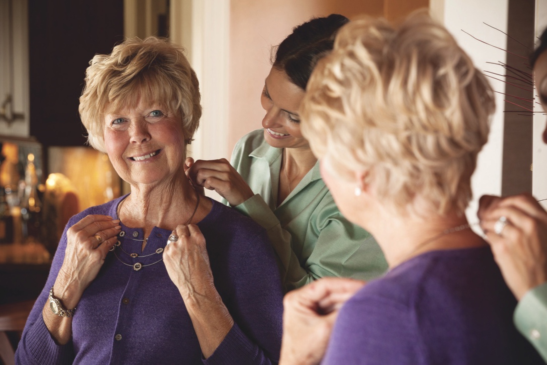 caregiver helping client put on necklace