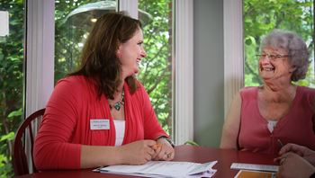 Woman helping client with homecare plans at a table