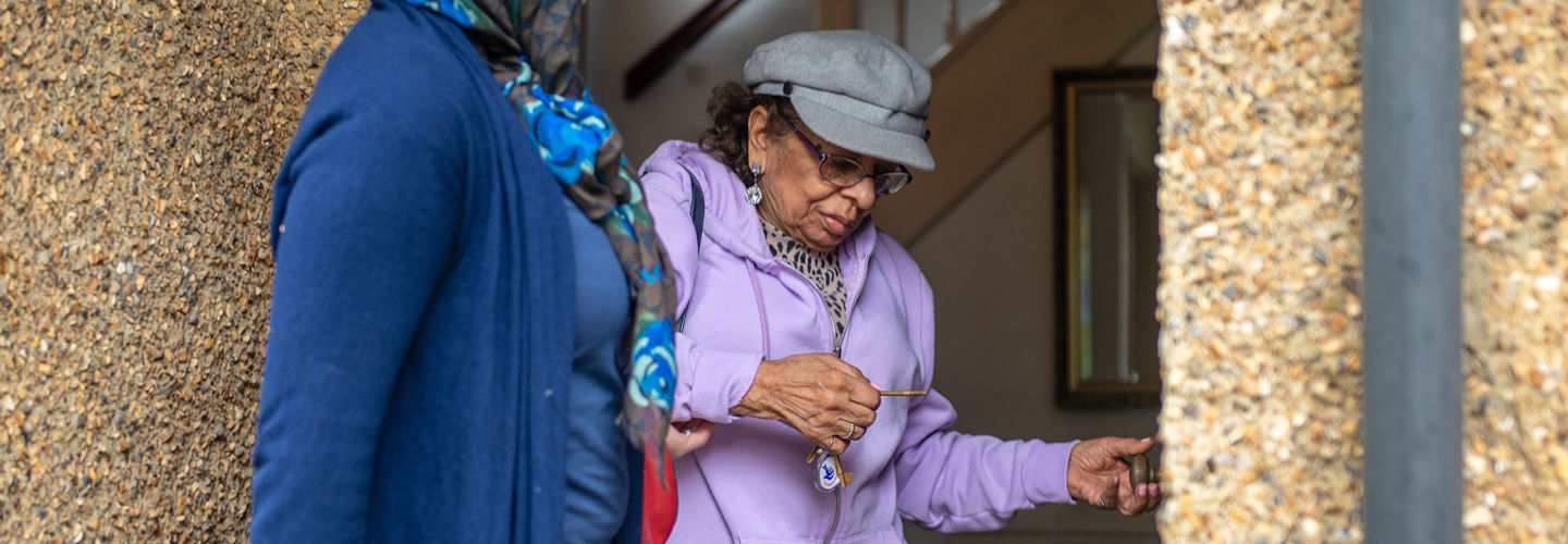 CareGiver standing with Client who is locking front door