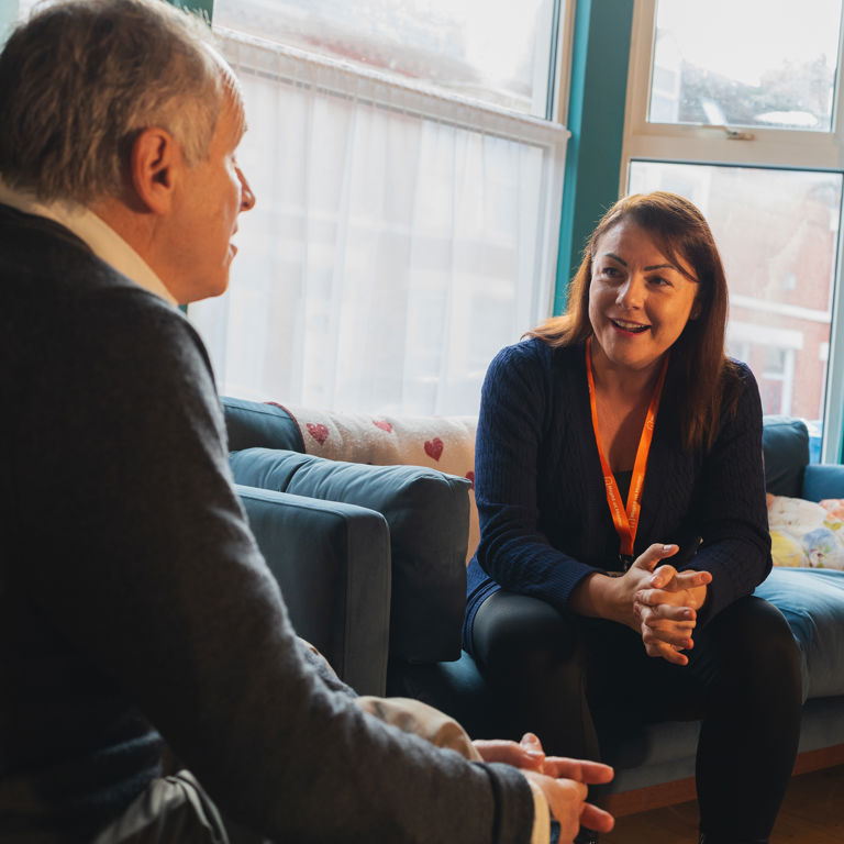 A female Carer sits and talks with an elderly male client